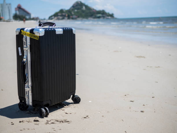 travel suitcase on a beach ocean in the background. - black blue escape multi colored imagens e fotografias de stock