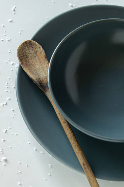 istock Grey empty ceramic plate with wooden spoon on salty white background . Minimal design. Space for text or menu 1160608301