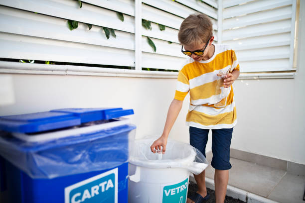 istock Little boy throwing out glass to segregated garbage bin 1160609260