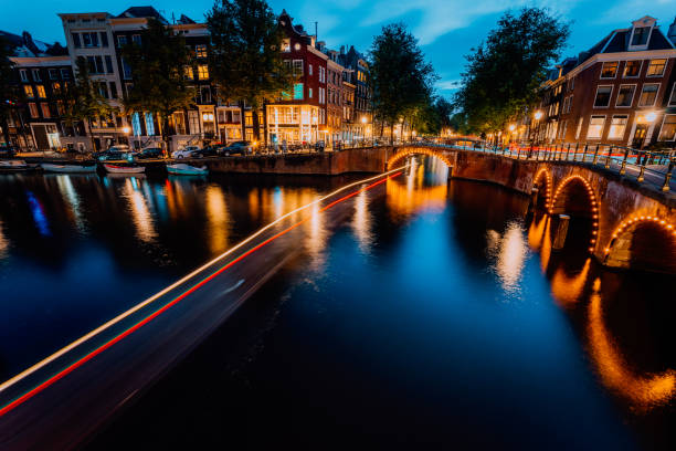 istock Amsterdam evening illuminated down town city. Touristic boat light trails and bridge reflections at the Leidsegracht and Keizersgracht canals. Long exposure shot. City trip visiting concept 1160610895