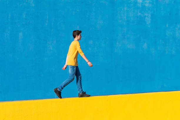 istock Young boy wearing casual clothes walking against a blue wall 1160611569