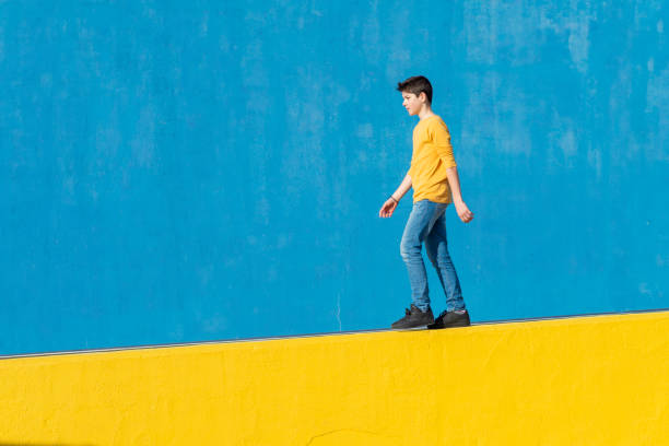 istock Young boy wearing casual clothes walking against a blue wall 1160611599