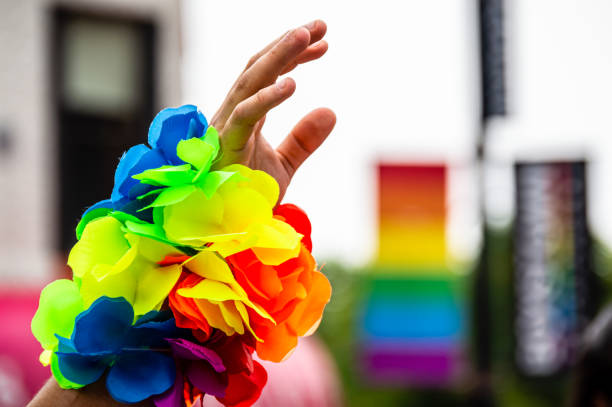 mano di un uomo in aria con un braccialetto arcobaleno alla parata del gay pride. - gay pride wristband rainbow lgbt foto e immagini stock