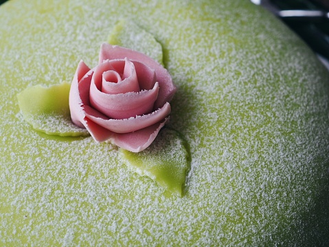 Green marzipan cake decorated with a pink rose of marzipan.