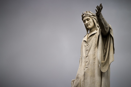 Statue of Dante Alighieri in Naples against the background of gray clouds, close-up