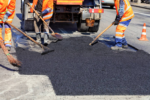 The working team smoothes hot asphalt with shovels by hand when repairing the road. The road workers' working group updates part of the road with fresh hot asphalt and smoothes it for repair. road construction photos stock pictures, royalty-free photos & images