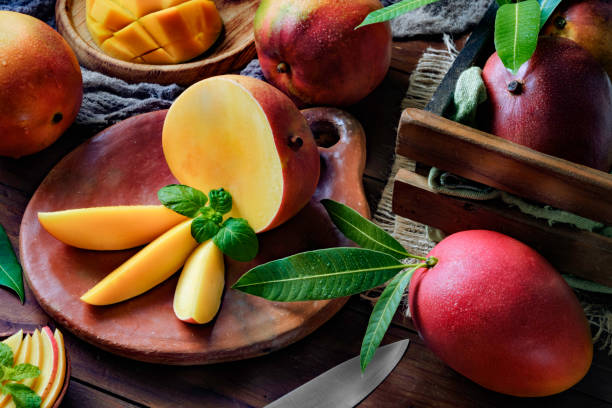 istock Tropical Fruits: Sliced mangos in a clay rustic plate on a wooden table in rustic kitchen 1160620417