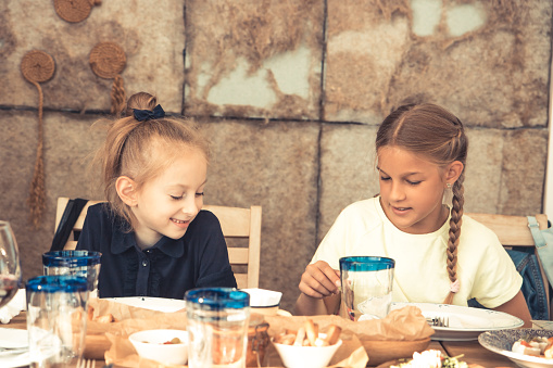 Happy children sister girls having a rest time in cafe restaurant talking together concept childhood lifestyle