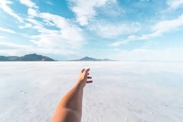 POV of a tourist experiencing the Bonneville Salt Flats in Utah on a beautiful summer day.