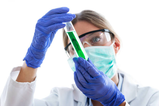 giovane scienziata donna con occhiali protettivi che guardano la provetta su sfondo bianco. - test tube biologist laboratory beaker foto e immagini stock