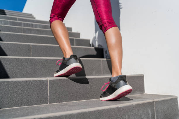 Running shoes runner woman walking up stairs Stairs climbing running woman doing run up steps on staircase. Female runner athlete going up stairs in urban city doing cardio sport workout run outside during summer. Activewear leggings and shoes. calf stock pictures, royalty-free photos & images