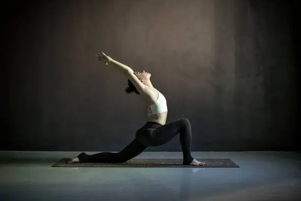 Photo of Woman doing hatha yoga asana Anjaneyasana or low crescent lunge pose