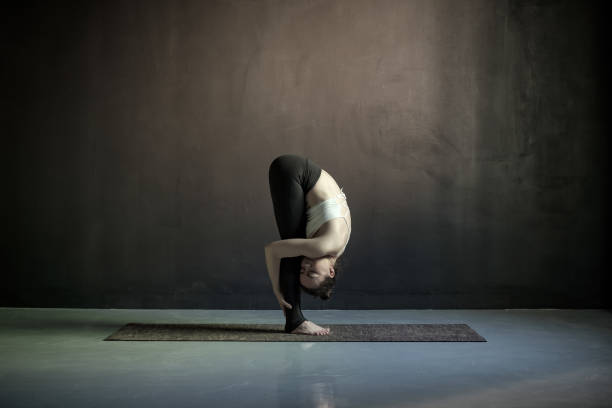 istock woman practicing yoga, doing head to knees, uttanasana exercise 1160629168