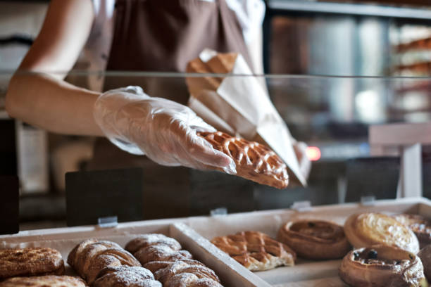 европейская женщина продает в пекарне положить хлеб в бумажный мешок. - bread bakery women cake стоковые фото и изображения