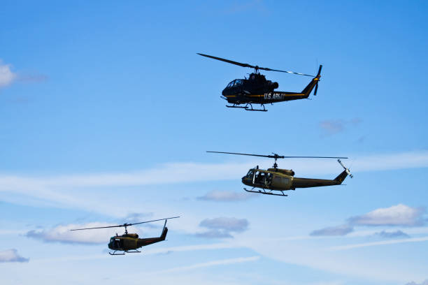 Bell UH-1 Iroquois Vintage Helicopter hovering Birmingham AL USA - October 13, 2018 : The Bell UH-1 Iroquois is a utility military helicopter powered by a single turboshaft engine, with two-blade main and tail rotors. Thi helicopter at a public event. In the picture the propeller airplanes flying slowly in front of general public. Even the clear blue sky is also visible in the picture. The vintage helicopter perform at various public events for years now. uh 1 helicopter stock pictures, royalty-free photos & images