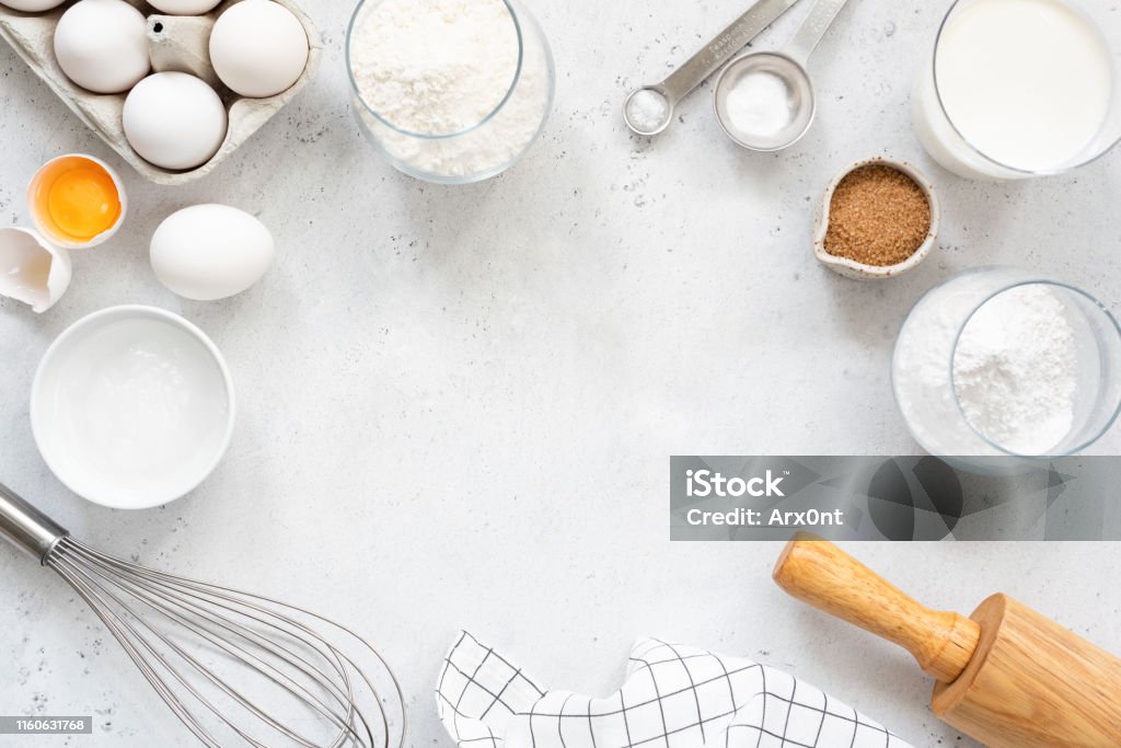Baking and cooking ingredients on bright grey background Frame of baking and cooking bread pastry or cake ingredients, flour sugar milk eggs and coconut butter on bright grey background with copy space for text, flat lay Baking Stock Photo