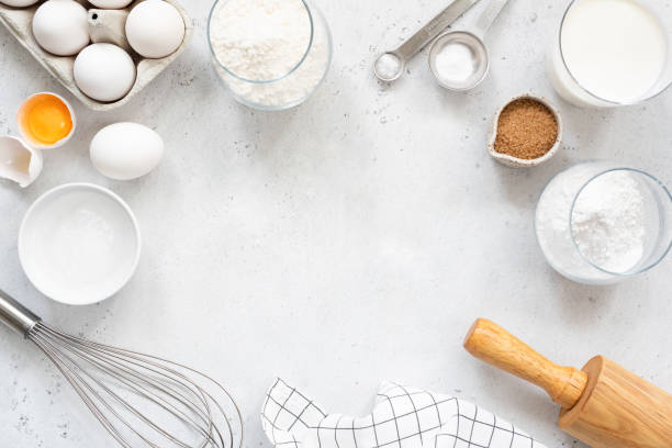 Baking and cooking ingredients on bright grey background Frame of baking and cooking bread pastry or cake ingredients, flour sugar milk eggs and coconut butter on bright grey background with copy space for text, flat lay baked stock pictures, royalty-free photos & images