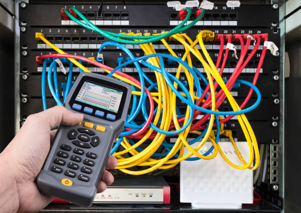 Network test. Qualified cable performance device in human hand detail. Structured cabling. Ethernet Data signal measurement. Diagnostic tester. Colorful cables connected in patch panels of rack case. Working IT specialist. Problem detection. Professional maintenance data cable stock pictures, royalty-free photos & images