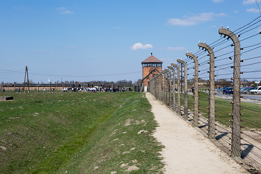 the Auschwitz-Birkenau concentration camp, located in Poland in Central Europe.  Visitors at the main gate in the background.