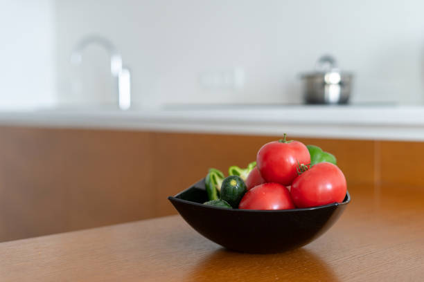 Bowl with vegetables on wooden table in kitchen room with modern interior