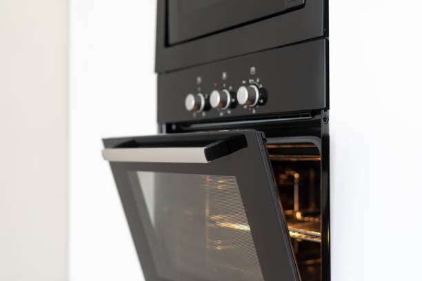 Modern built in oven with open glass door on white kitchen Selective focus of black and modern built in oven with open glass door on white contemporary kitchen oven door stock pictures, royalty-free photos & images
