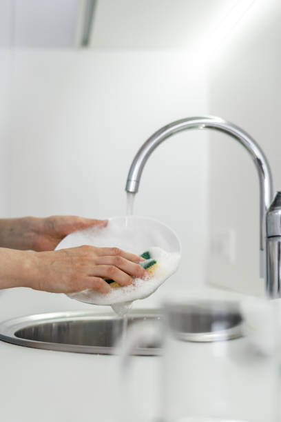 istock Woman using sponge with foam, washing plate in sink at white kitchen 1160634691