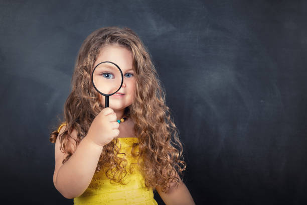 istock Little curious school girl with magnifier on chalkboard 1160634846