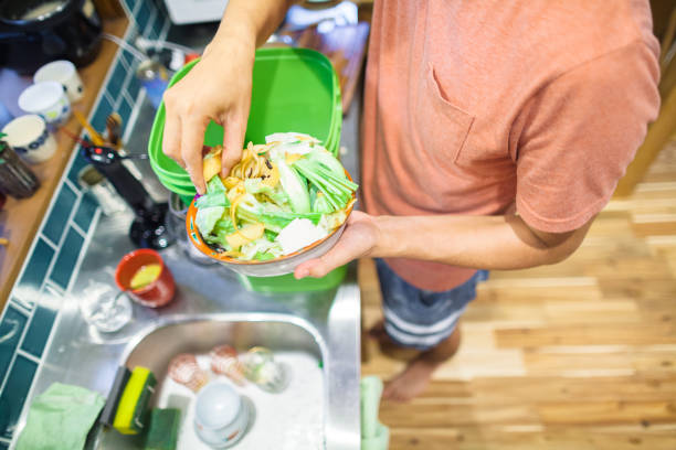 istock Man putting food left over into composter 1160637648