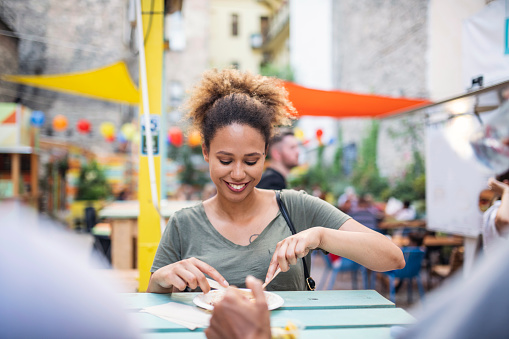 African American woman eating local street food with her friends in Budapest