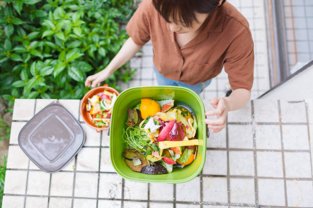Woman putting food garbage into composter