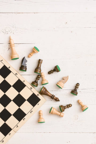 istock wooden chess figures and part of a chess board on white table background. Top view. 1160640764
