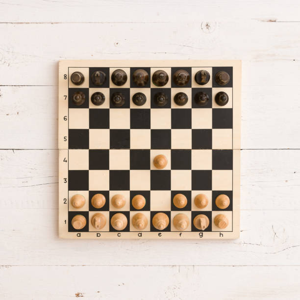 istock Top view on wooden chess board with figures on white wooden table background. First chess move. 1160641338