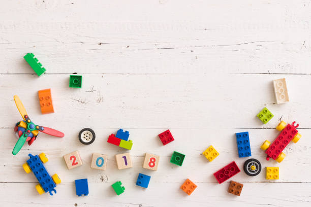 istock Top view on plastic toys, details, bricks and wheels on white wooden table background 1160641378