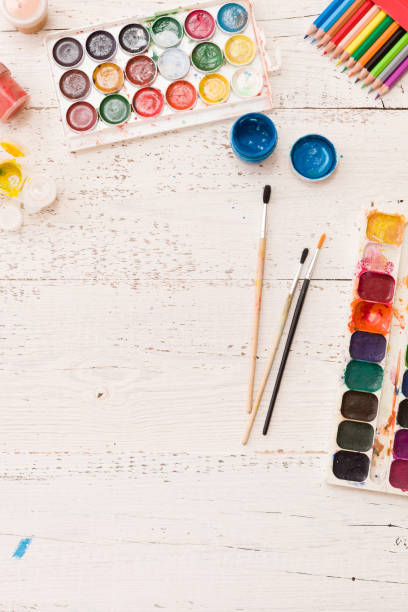 istock Top view on paints and brushes on white wooden table background. 1160641453