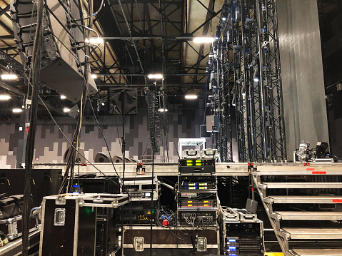 Installation of professional sound, light, video and stage equipment for a concert. Backstage area and tech zone with amplifiers, flight cases and radio microphones.