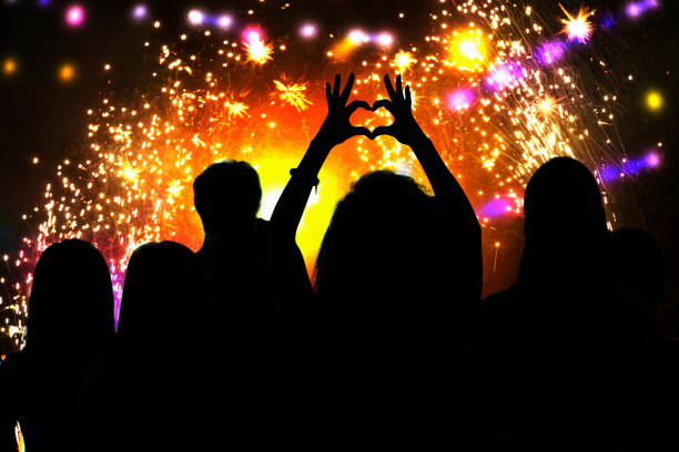 vue arrière de la silhouette de jeune femme faisant le symbole de forme de coeur à la célébration de feu d'artifice - fireworks show photos et images de collection