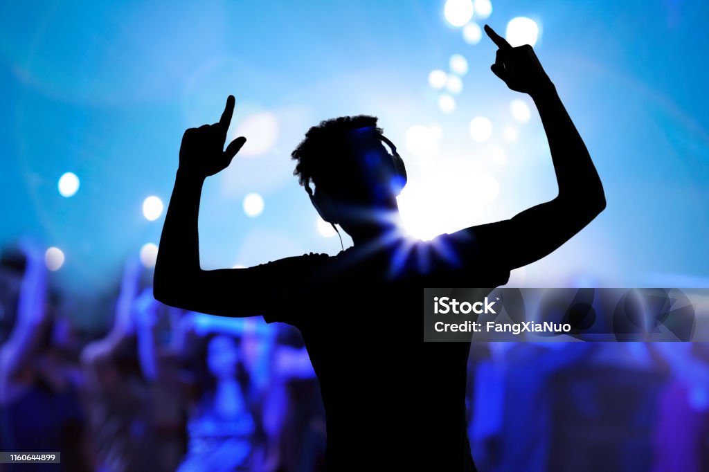 Cheering disco DJ performing with arm raised at concert music festival DJ Stock Photo