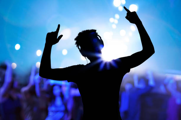 Cheering disco DJ performing with arm raised at concert music festival Cheering disco DJ performing with arm raised at concert music festival dance & electronic music stock pictures, royalty-free photos & images