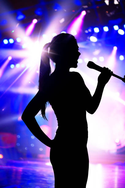 Silhouette of woman with microphone singing on concert stage Silhouette of woman with microphone singing on concert stage hair band stock pictures, royalty-free photos & images