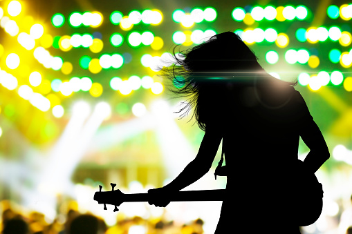 Silhouette of musician playing on guitar on concert stage