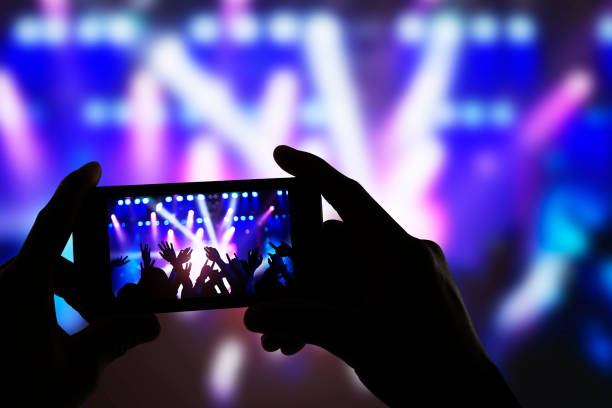 Hands holding smart phone and recording concert stage at live music performance Hands holding smart phone and recording concert stage at live music performance photo messaging stock pictures, royalty-free photos & images