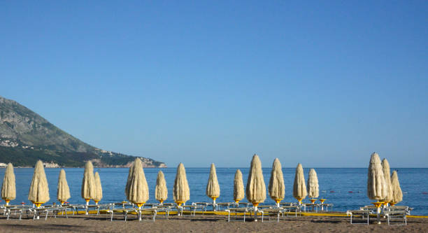 istock Parasols, deck chairs and yellow footpath on the sandy beach 1160647393