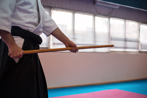 Fighter in kimono holding  wooden sword at the gym