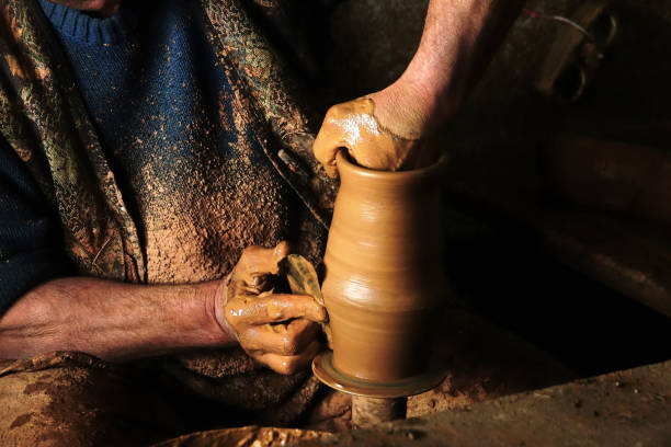 istock mud covered hands of adult man making clay pot 1160655049