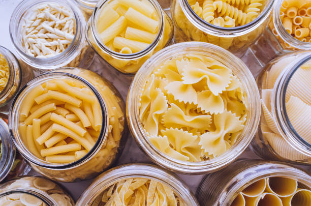 Variety of types and shapes of Italian pasta Variety of types and shapes of Italian pasta in glass jars on marble background. Italian cuisine food storage concept. Top view. Copy space. noodles stock pictures, royalty-free photos & images