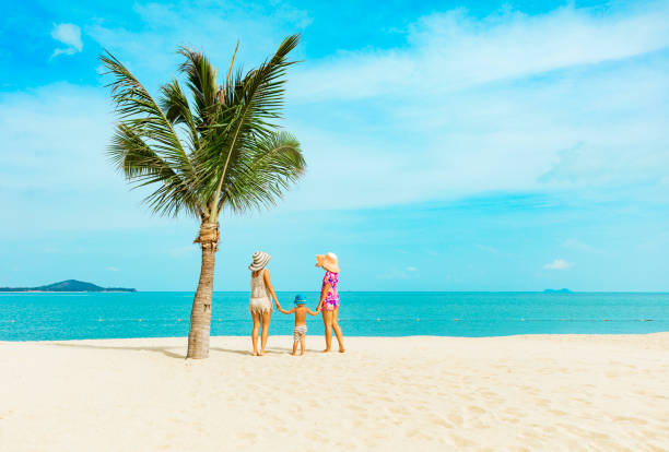 two woman with baby boys at tropical beach