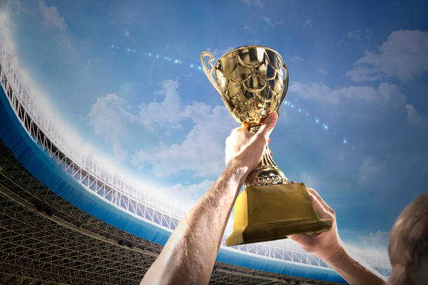 istock Athlete holding trophy cup above head in stadium 1160660684