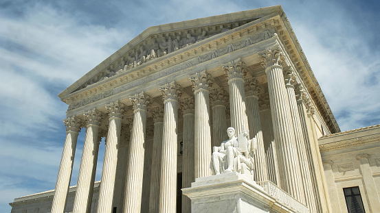 oblique shot of the us supreme court building and the statue, authority of law, in washington d.c.