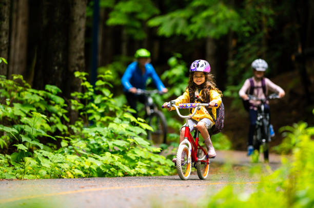 madre e hija en bicicleta en el bosque - helmet bicycle little girls child fotografías e imágenes de stock