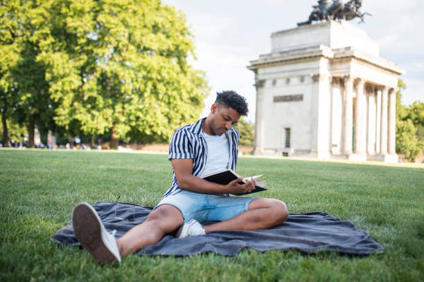 istock Relaxed Mixed Race Man Enjoying a Book in a London Meadow 1160666875